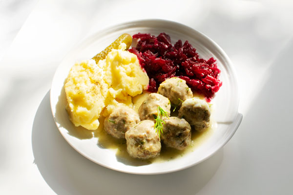 Polish meatballs (Pulpety) in dill sauce, served with mash potatoes and beetroot salad on a white plate, on a white background. Horizontal image.
