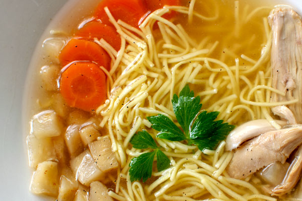 Close up of Rosół: Polish Chicken Soup with thin egg Noodles. Served with sliced carrots, parsnip root and chicken meat.