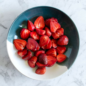Top view of a bowl full of halved strawberries