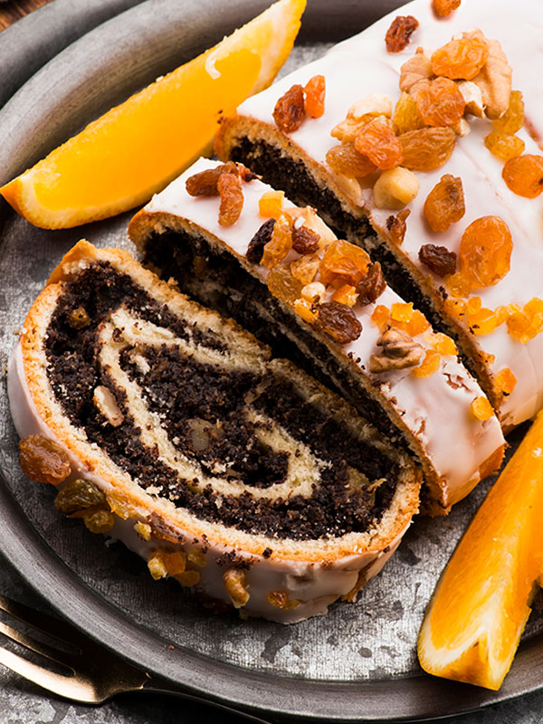 Poppy Seed Roll decorated with frosting, raisins and nuts.