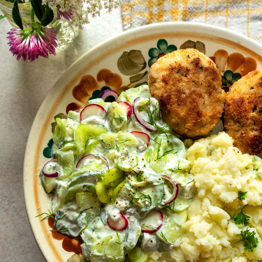 Mizeria (Polish cucumber salad) served with mashed potatoes and pork patties (kotlety mielone)