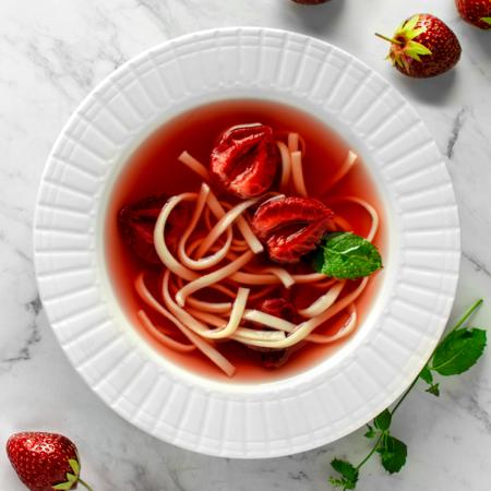 Polish Strawberry Soup, Served with Egg noodles. Flat lay/ view from above, served on a white plate, on a white marble table.