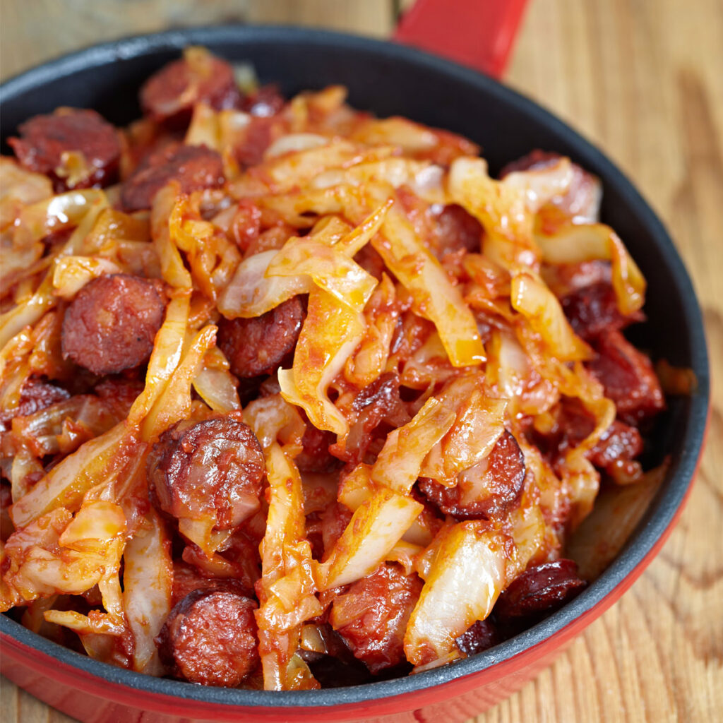 Skillet with with cooked cabbage with Polish sausage (kielbasa)