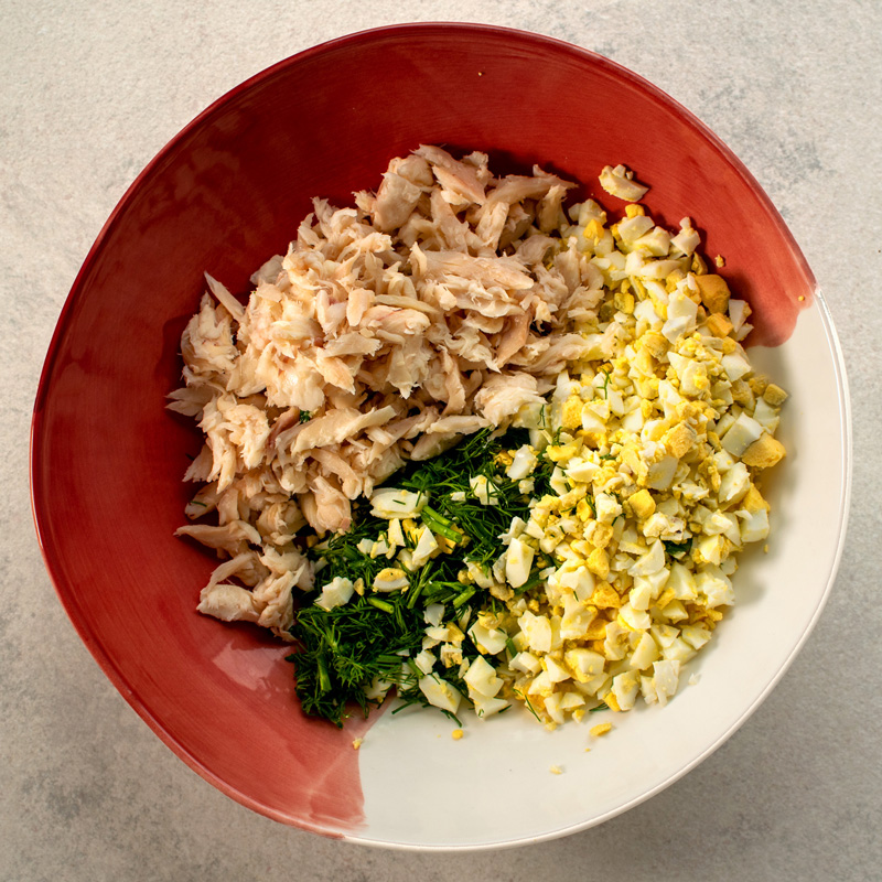 Smoked trout flakes, chopped eggs and chopped herbs in a bowl.