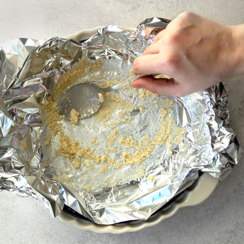 Covering aluminum foil with a spoonful of grated horseradish.